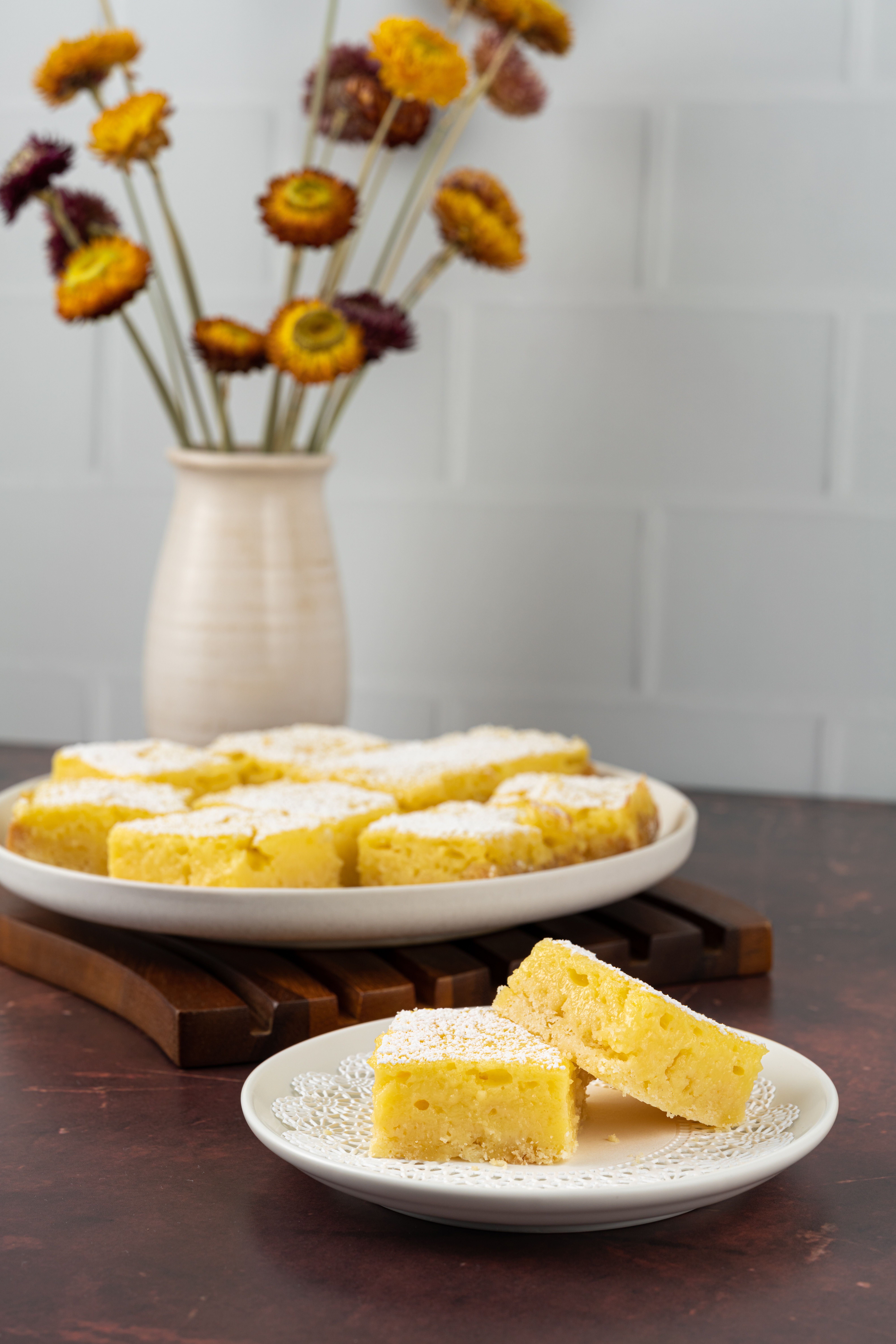 Golden squares of sweet cornbread stacked on a wooden board, with a pat of butter melting into the top slice.