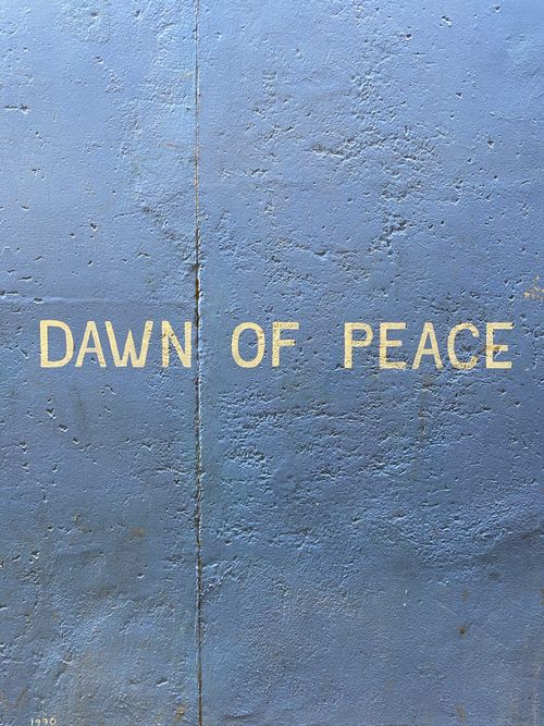 Free Close-up of 'Dawn of Peace' text on rough concrete wall background. Stock Photo