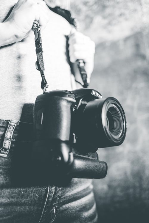 Free Monochrome image showing a person holding a DSLR camera, focusing on photography gear. Stock Photo