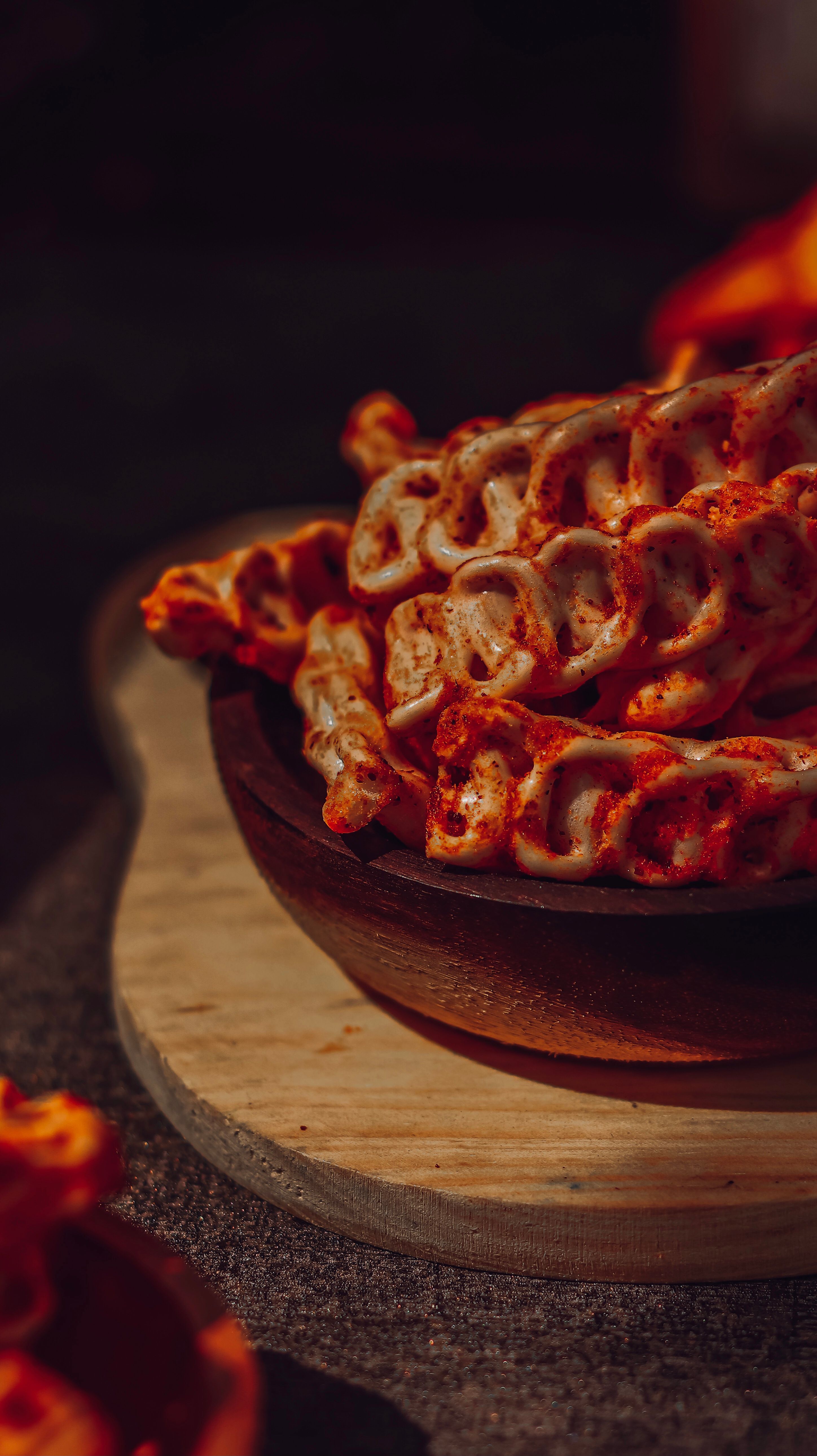 Close-up of spicy seasoned pretzels in a rustic wooden bowl, perfect for snacking.