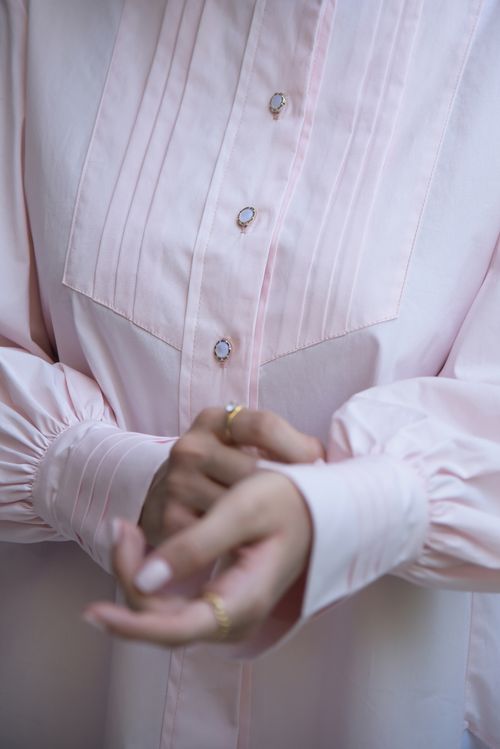 Free Close-up of a person adjusting a pink blouse with elegant buttons, showcasing clothing style. Stock Photo