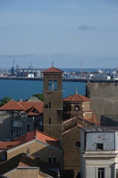 Aerial view of a coastal cityscape featuring historic architecture and a scenic ocean backdrop.