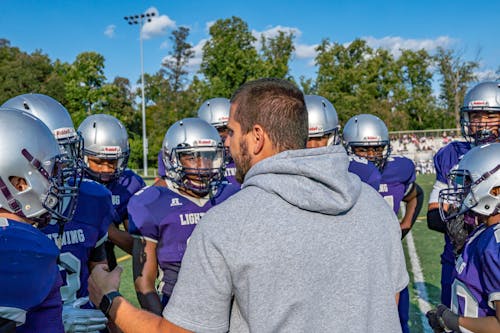 Free A Man in Gray Hoodie Huddling a Football Team Stock Photo