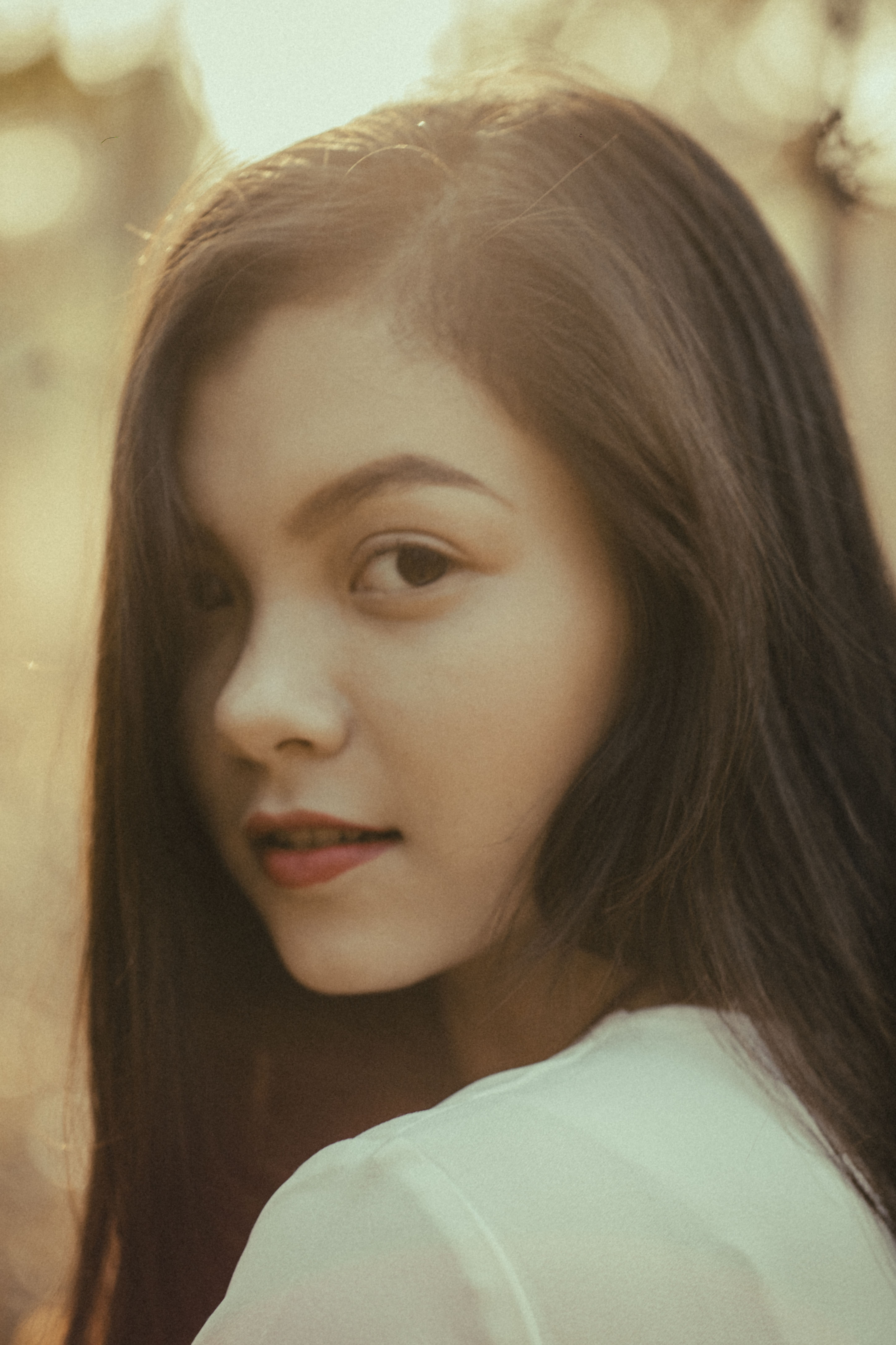 A captivating portrait of a young woman with a soft, warm glow outdoors.
