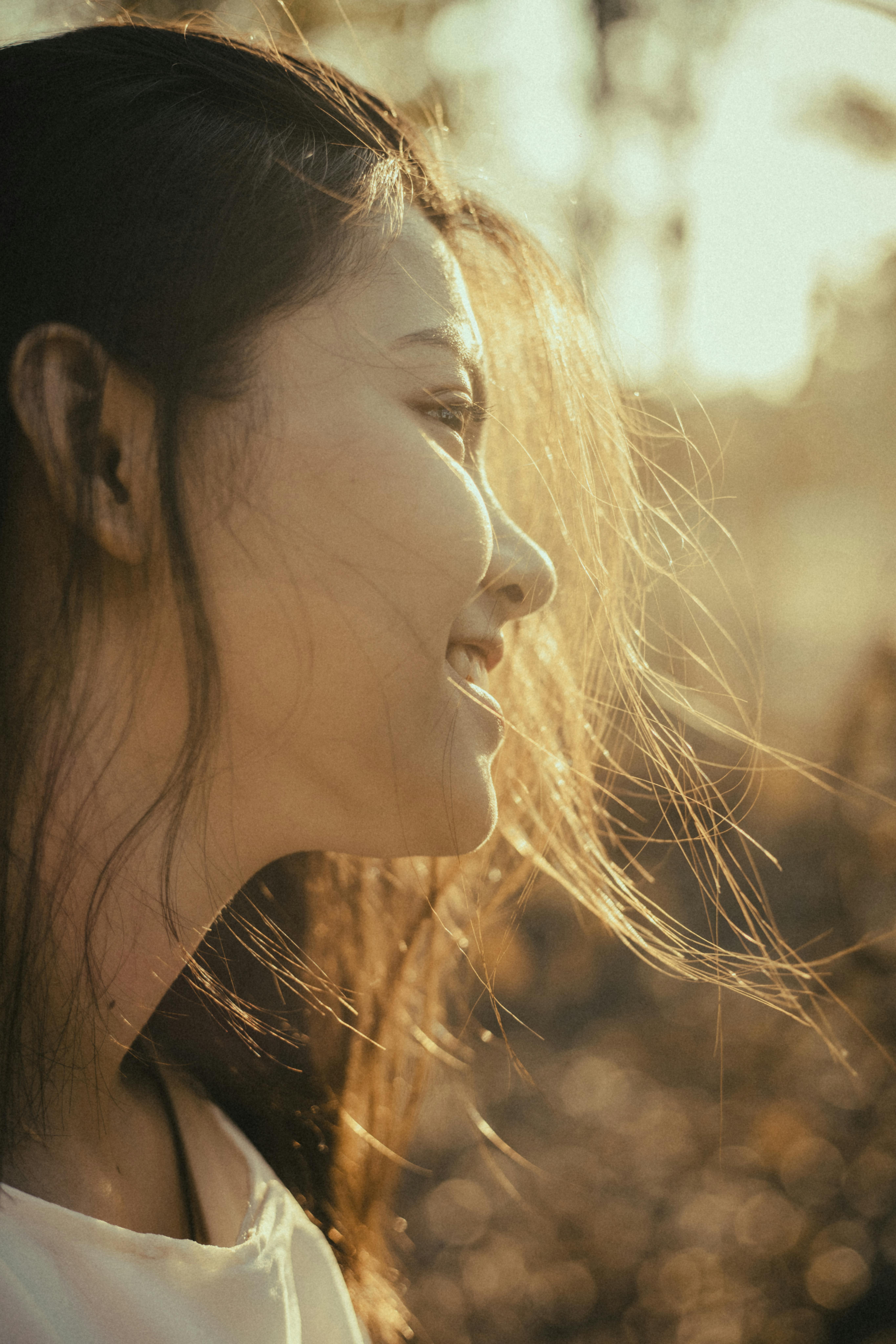 Portrait of a woman smiling peacefully in a sunlit setting, capturing a serene moment.