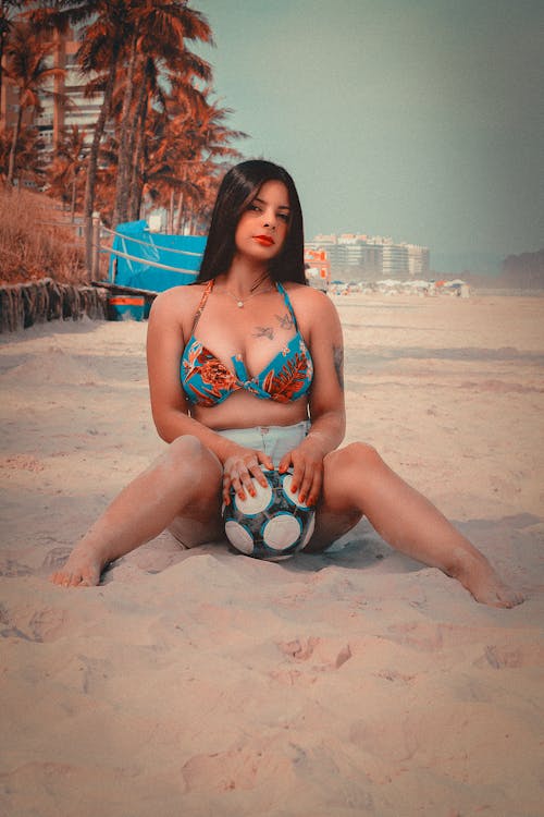 Beautiful Woman in her Bikini in the Beach Holding a Football