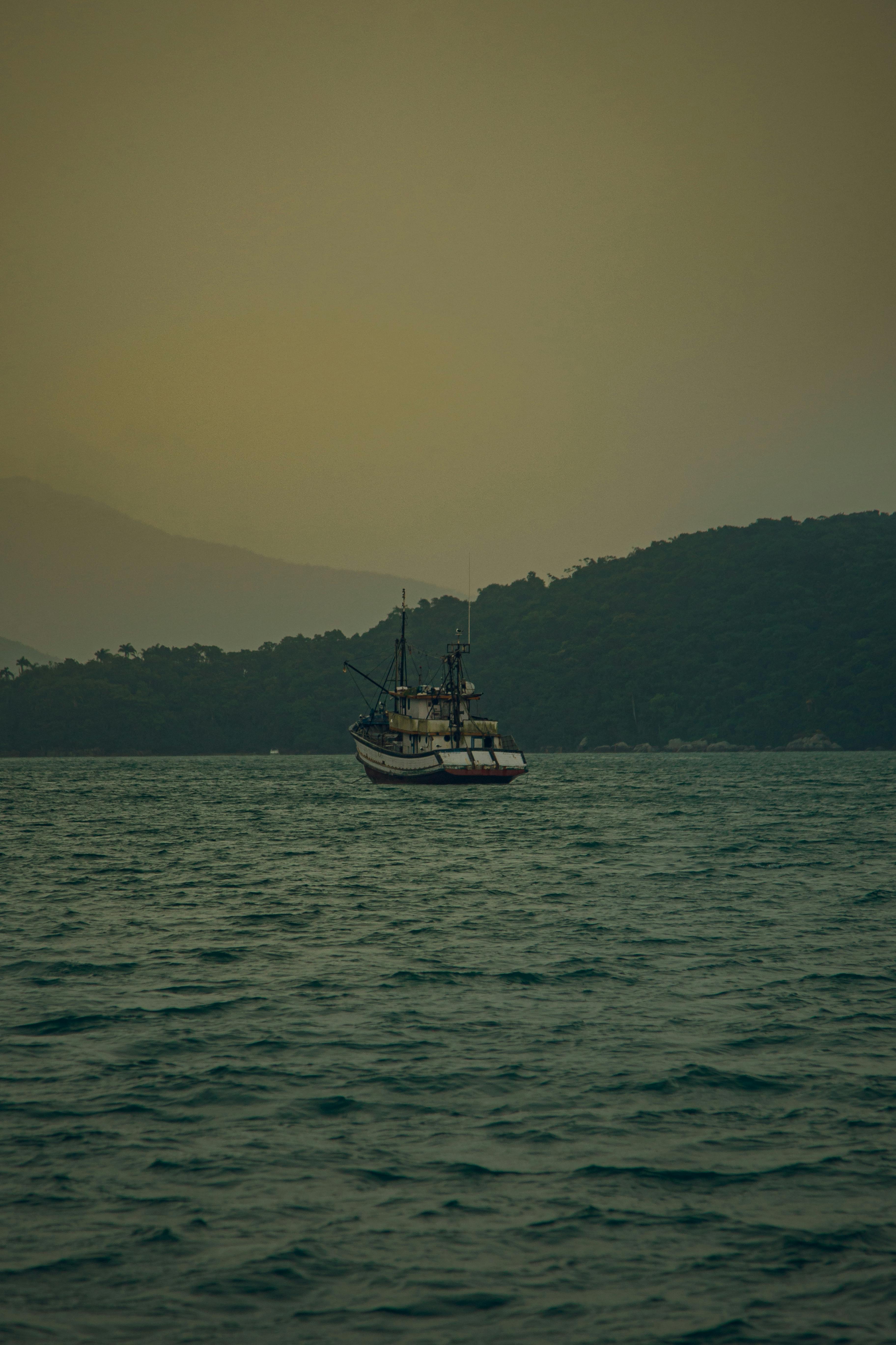 Free A serene fishing boat anchored in the calming waters of Porto Belo, Brazil at dusk. Stock Photo