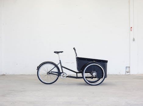 Side view of a three-wheeled cargo bike in a minimalistic indoor setting.