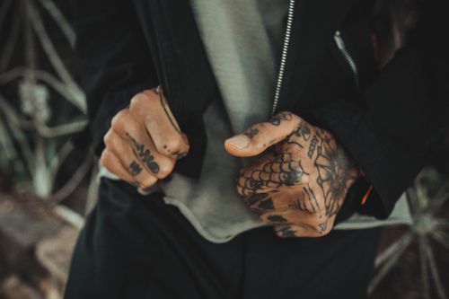 Free Close-up of tattooed hands in an urban outdoor setting, capturing intricate designs and modern fashion. Stock Photo