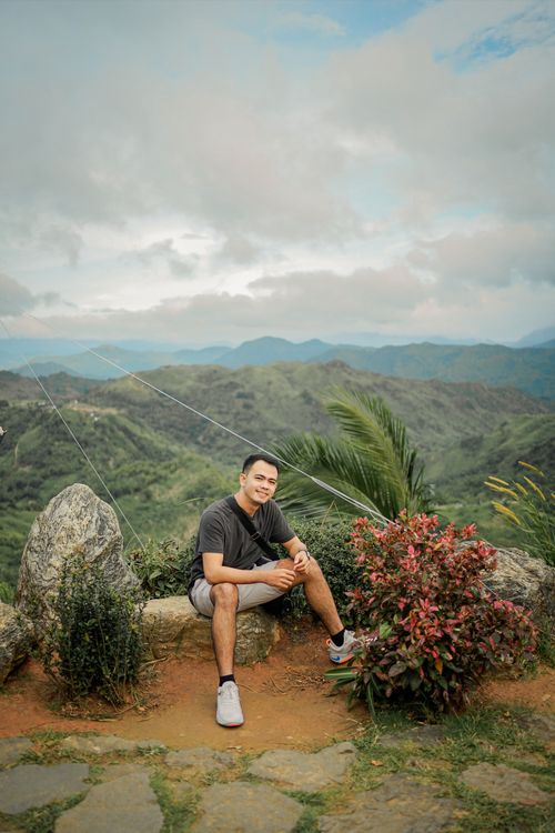 Free A man sitting on a rocky path with a stunning mountain view in the background, exuding tranquility. Stock Photo