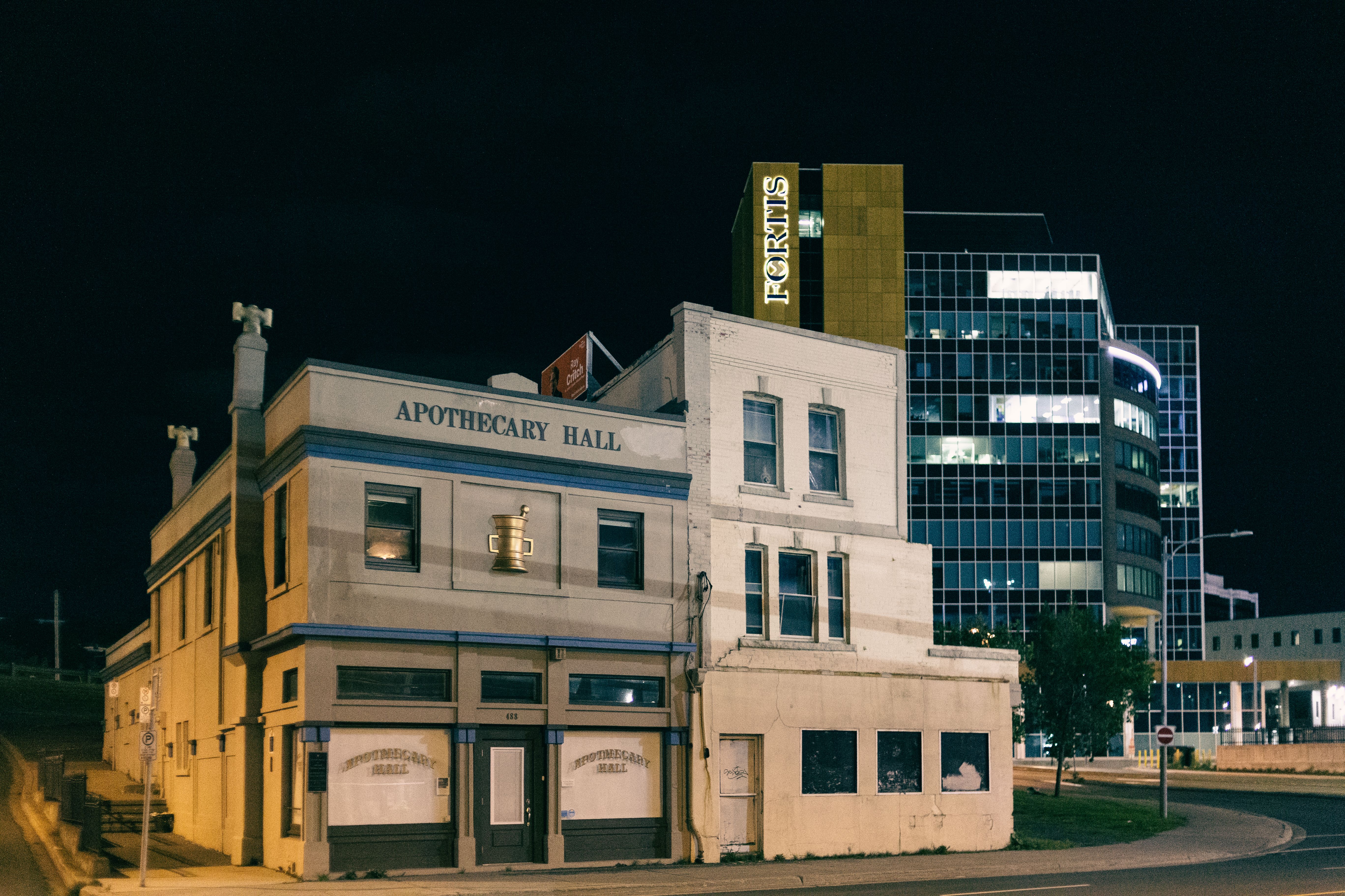 Night view of the Apothecary Hall and modern glass building in urban setting.