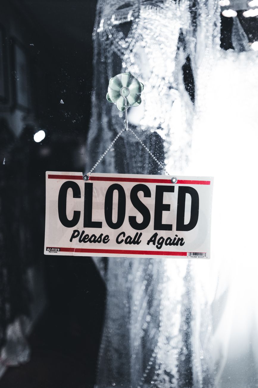 Photo by Erik Mclean A 'Closed' sign hangs on a glass door, urging visitors to 'Call Again.'