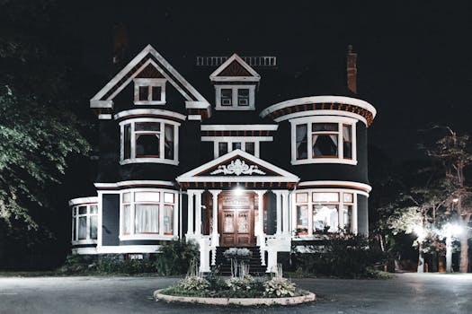 Stunning Victorian-style house illuminated at night, showcasing classic architectural elegance.