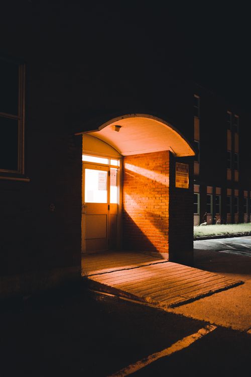 Free A warmly lit doorway at night creates an inviting entrance in an urban building. Stock Photo