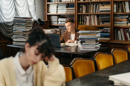 A young man deeply focused while reading in a cozy, well-stocked library.