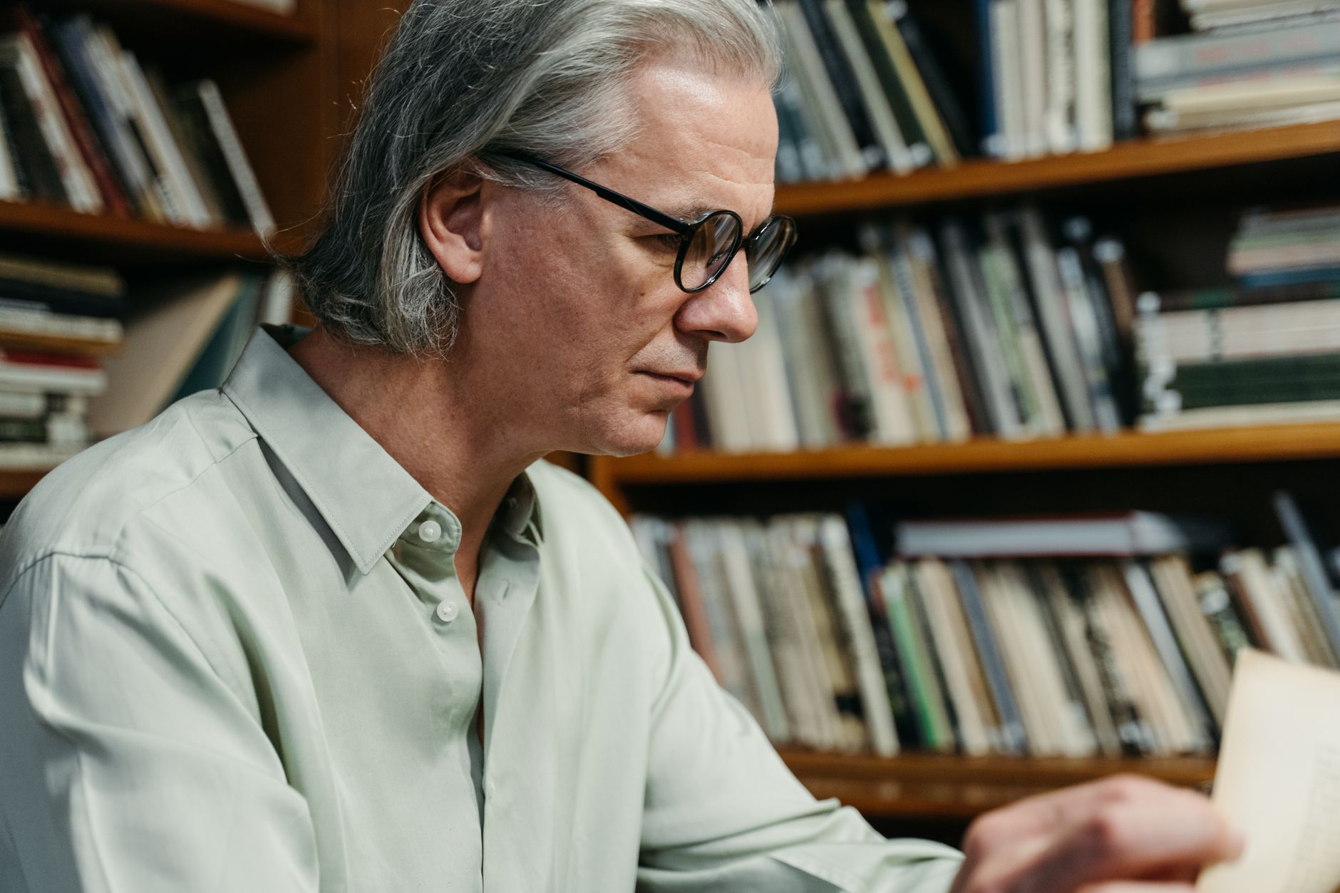 a wealthy middle-aged bettor studying football player ranking sheets under a desk lamp at night
