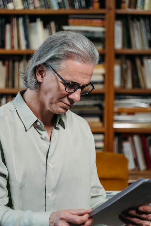A Long-Haired Man in Eyeglasses Reading a Document