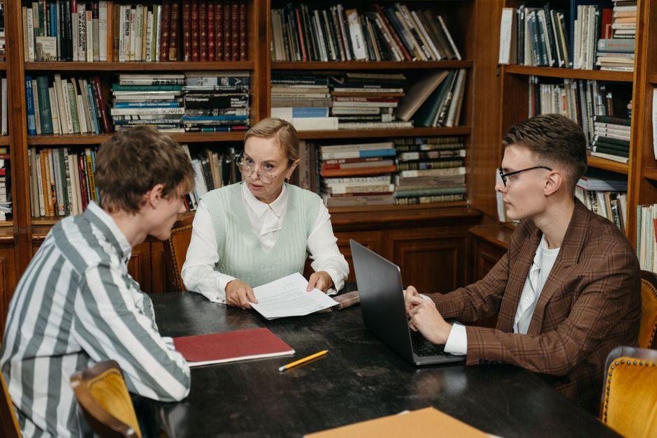 How to Fix AI Text for Professors: 7 Humanizing Steps 2 A group of adults engaged in conversation around a table in a library setting.