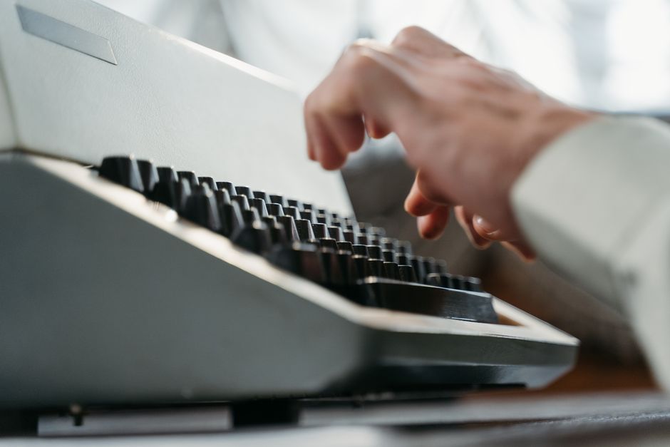 Detailed shot of hands typing on an antique typewriter, showcasing vintage technology.