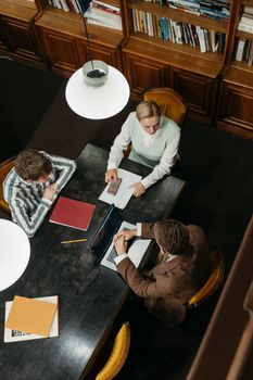 A group of students discussing a project in a cozy university library setting.
