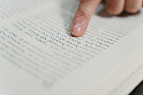 A Person's Finger Pointing on the Text of a Book 