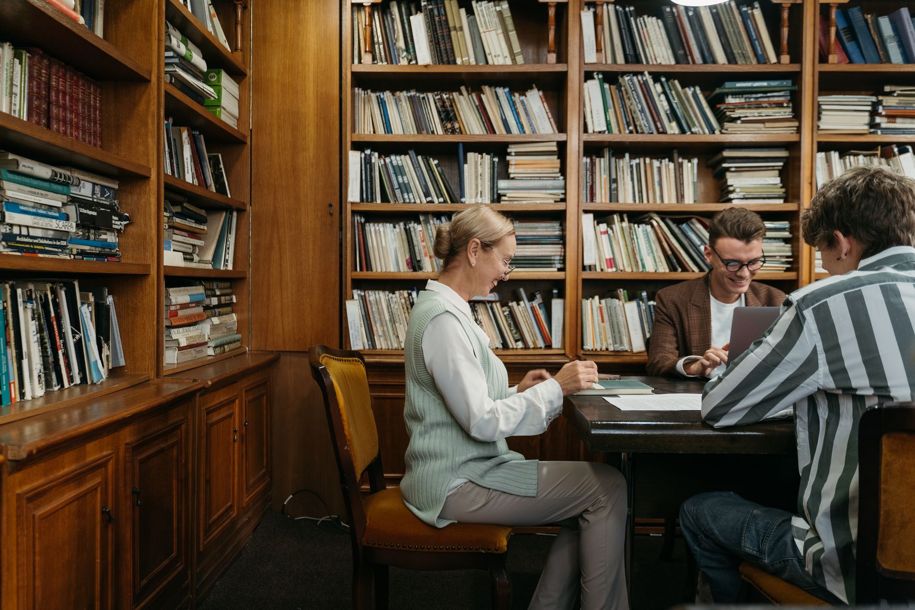 Colleagues meeting at a table in a wood-paneled library