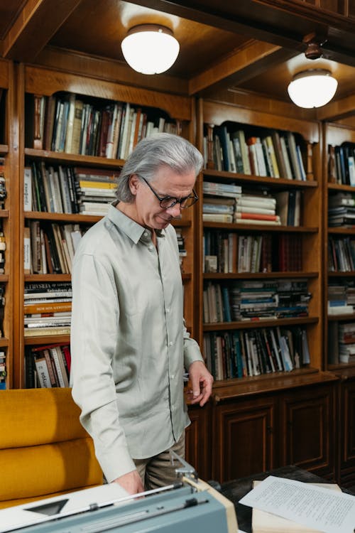 A Man Standing Beside Wooden Bookshelf