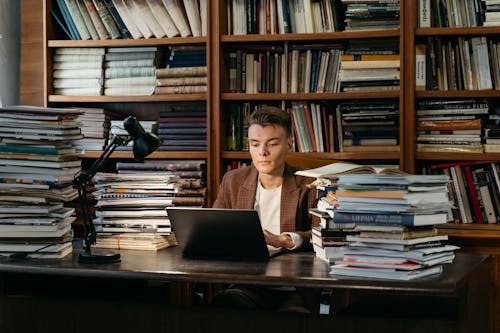 Man Sitting on Chair while Using His Laptop in the Library