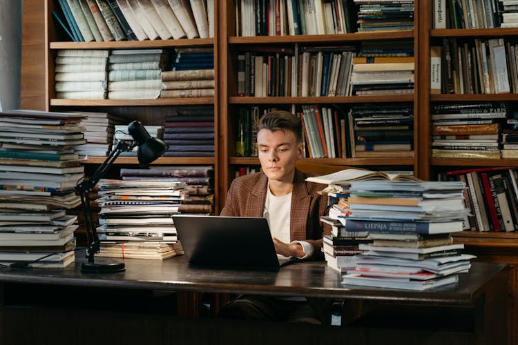 Man Sitting On Chair While Using His Laptop In The Library