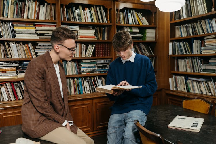 College Students Reading A Book Inside The Library