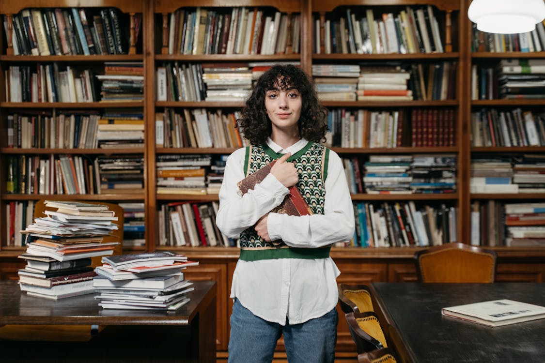 Free A Woman Wearing a Vest over a Dress Shirt Holding a Book Stock Photo