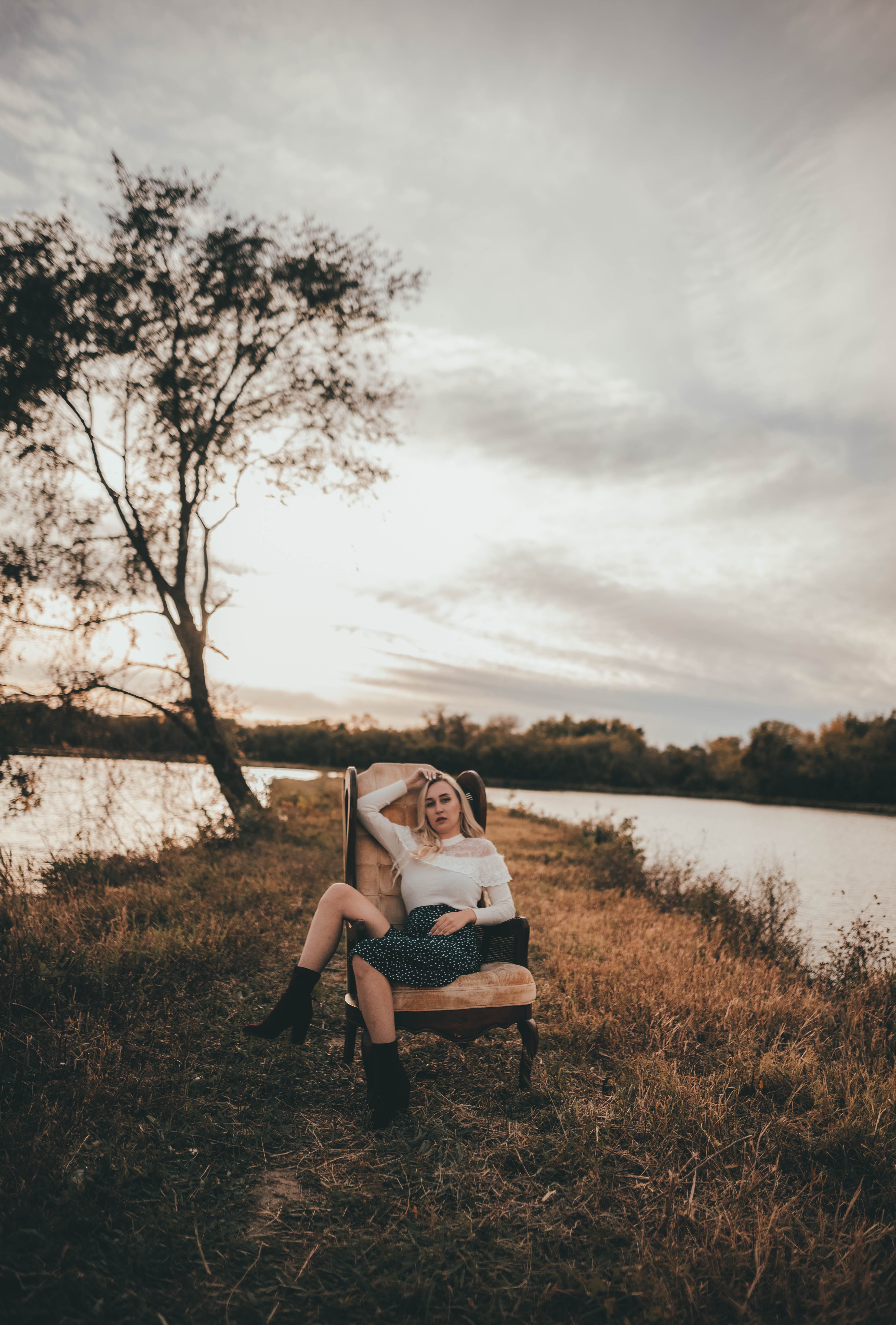 Blonde Woman Sitting on Chair Near Lake · Free Stock Photo