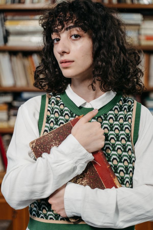 Woman in an evergreen sweater vest with a white shirt and jeans