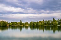 长时间曝光拍摄下，宁静的湖泊映着树木倒影和戏剧性的多云天空