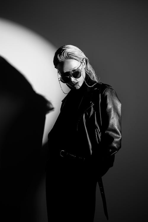 Grayscale Photo of a Woman in Black Leather Jacket Wearing Sunglasses
