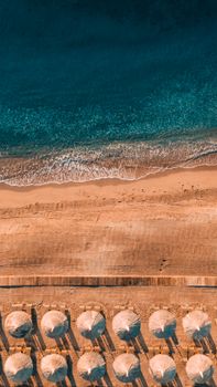 Stunning aerial view of a sandy beach lined with umbrellas alongside a turquoise sea. Perfect for travel and summer themes.