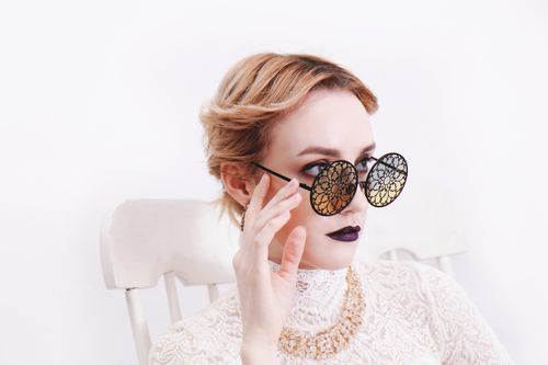 Free Elegant woman posing in a lace top, adorned with a diamond necklace, exuding glamour and style in a studio setting. Stock Photo