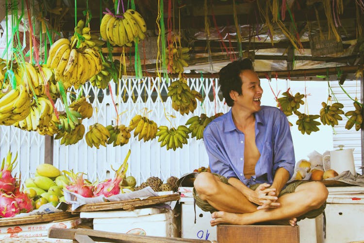 Man Sitting Beside Hanging Bananas 