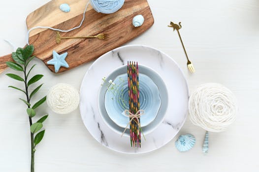 Elegant flatlay of porcelain tableware, knitting yarns, and decorative elements on a wooden board.