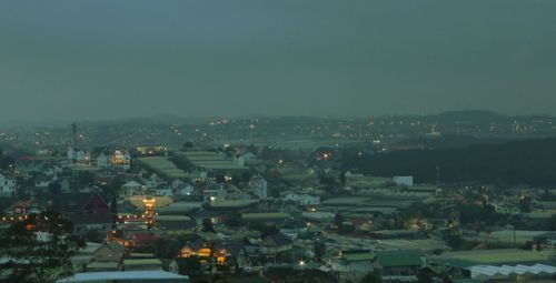 Free A panoramic view of a foggy cityscape with evening lights illuminating houses and streets. Stock Photo