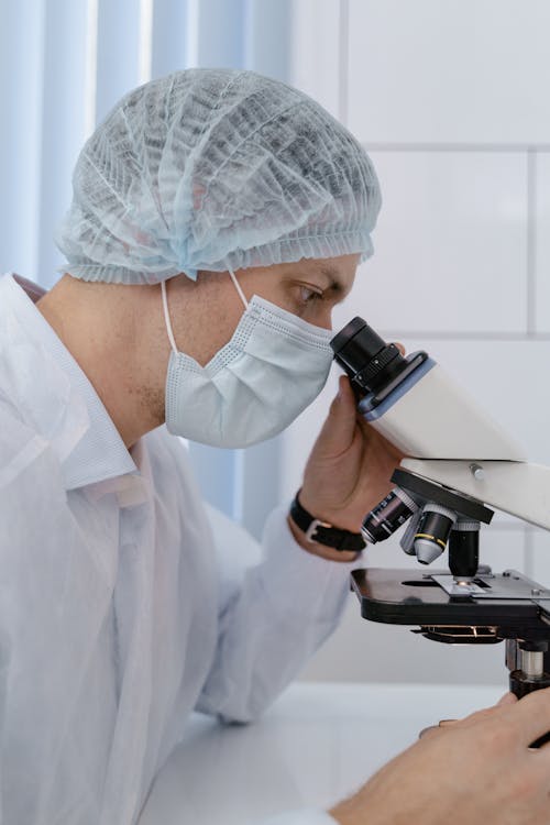 A Man Looking Through a Microscope · Free Stock Photo
