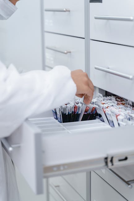 A person wearing a lab coat organizing files in a medical laboratory drawer.