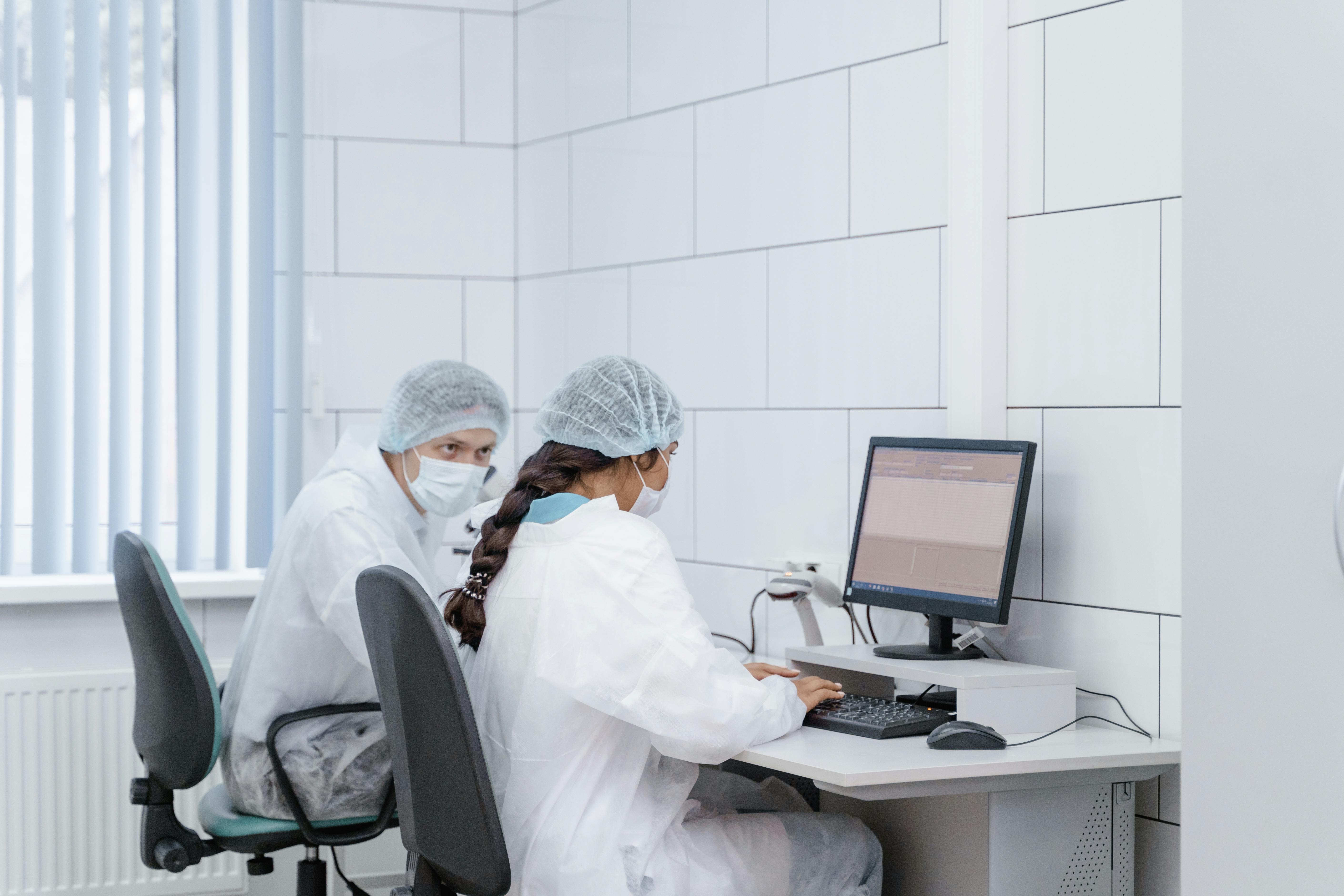 Two scientists at a computer in a laboratory setting, analyzing data with focus and precision.