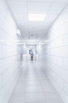 Clean and sterile hospital hallway with a single medical professional in view.