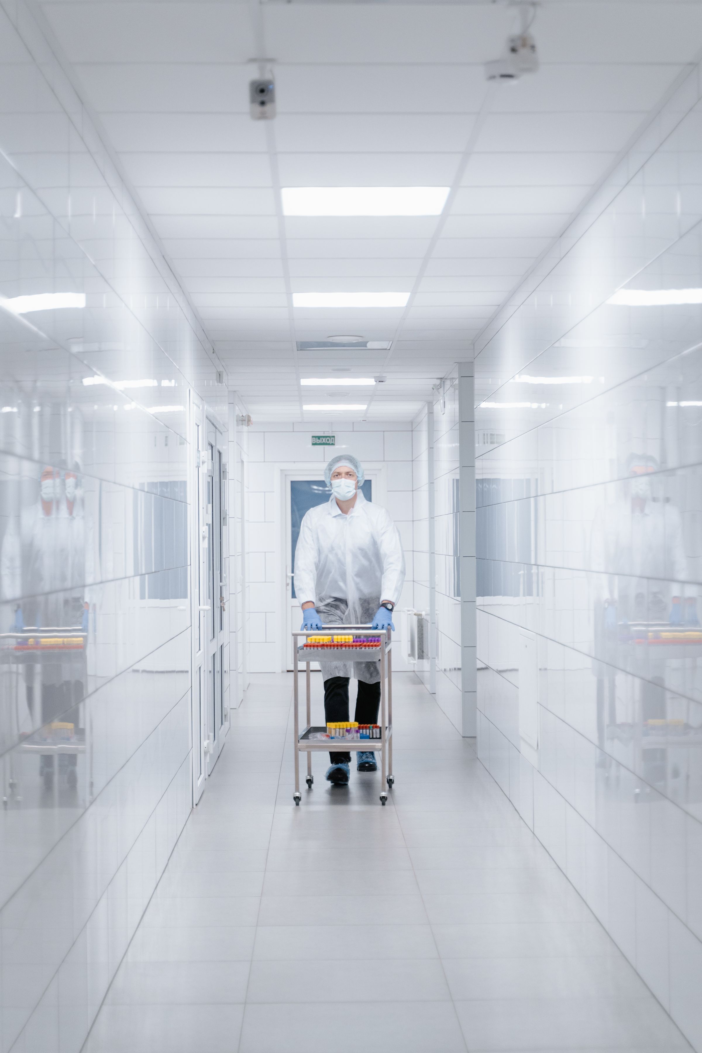 An operator in full gowning moves a cart through a sterile corridor