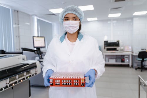A Person Wearing Face Mask while Holding a Test Tube Rack