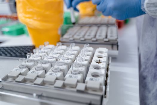Close-up of test tubes in a lab setting with a technician handling samples. Ideal for scientific research visuals.