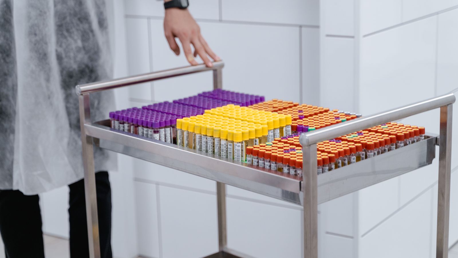 Organized laboratory test samples in colorful capped vials on a steel cart.