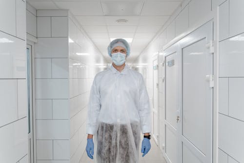 Man Wearing Face Mask and Protective Suit Standing in the Corridor
