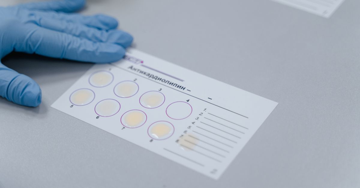 person journaling with blood test results and a microscope